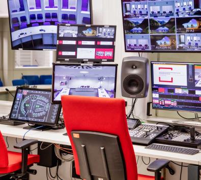 Arbeitsplatz mit mehreren Bildschirmen und Geräten