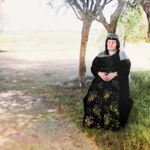 Eine georgische Frau in traditioneller Kleidung posiert unter einem Baum für den Fotografen.