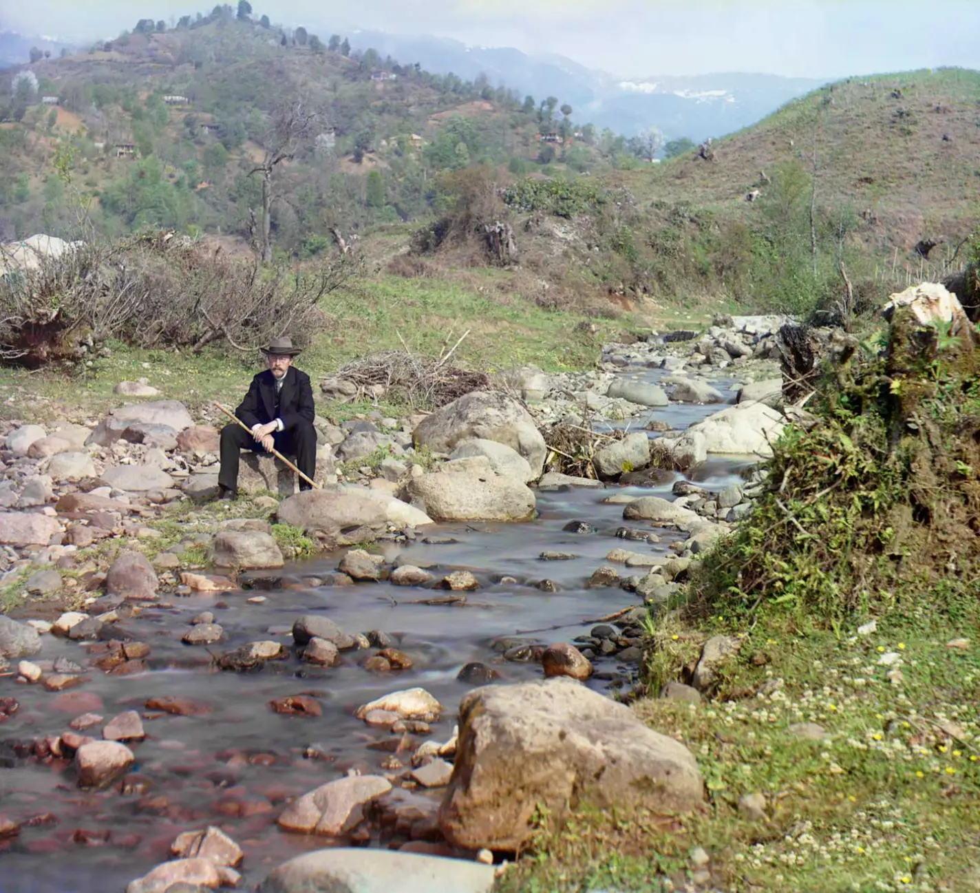 Selbstbild von Sergej Prokudin-Gorskij mit Anzug und Hut am Korolistskali-Fluss nahe Batum. Im Hintergrund Berge.