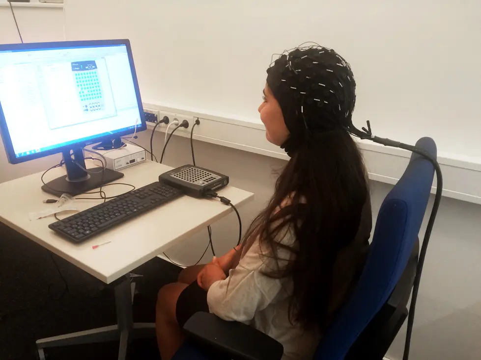 Frau mit Haube und Elektroden vor PC