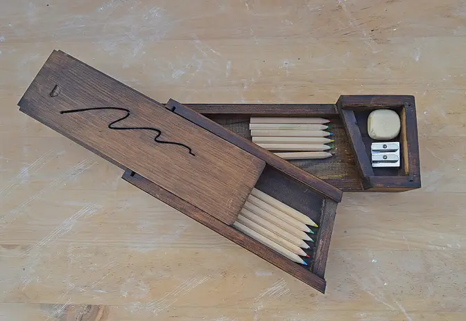 Holzkästchen mit Buntstiften, Radierer und Anspitzer
