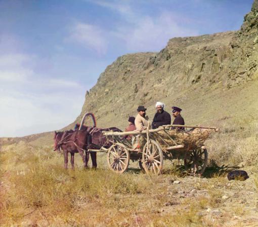 Vier Männer – in einer von Pferden gezogenen Kutsche reisend – während einer Pendelfahrt in der Golodnaia-Steppe, Kirgisien